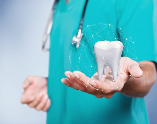 The concept of dental treatment. Doctor shows a tooth in his hand.
